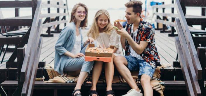 Three friends sharing a pizza and laughter.