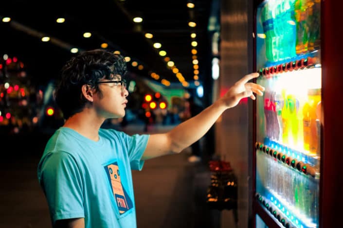 man choosing drinks in vending machine 
