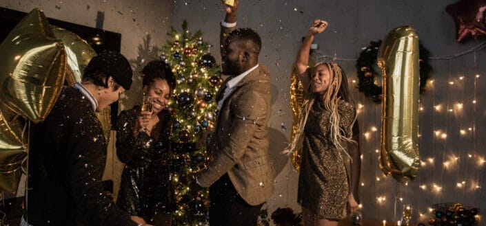 group of friends dancing near a christmas tree