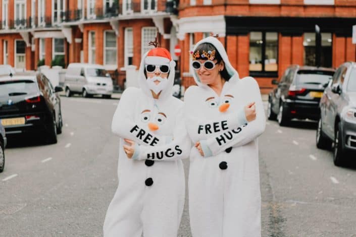 two people wearing white snowman overalls with free hugs print
