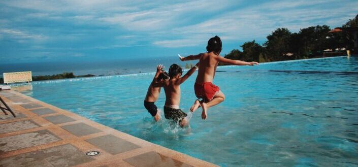 three little boys jumping into a pool