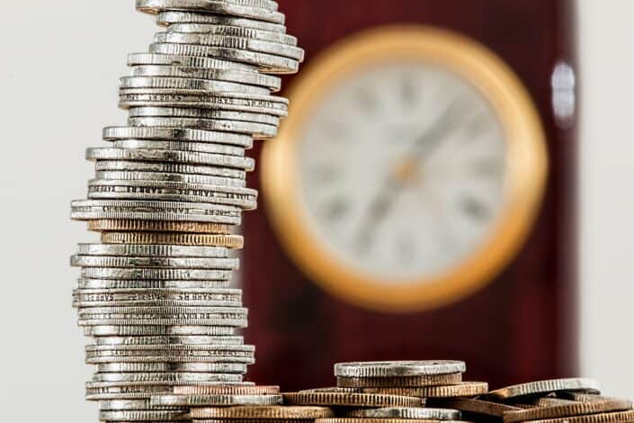 Stack of coins with clock in the background