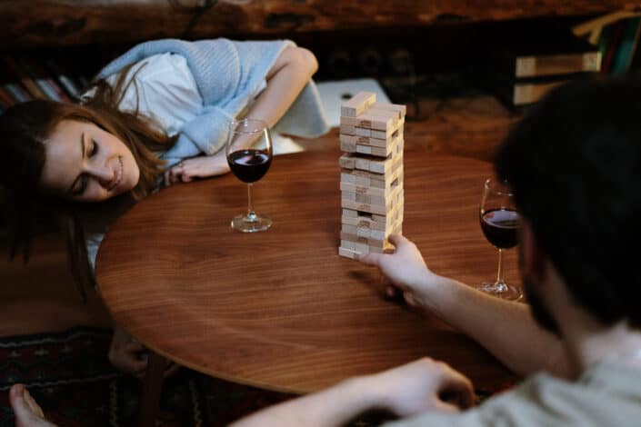 man and woman playing jenga over a glass of wine