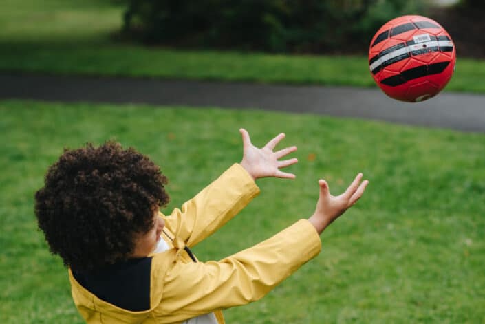 curly haired boy throwing soccer ball