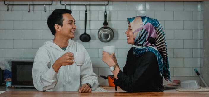 muslim couple smiling at each other with a cup on their hands