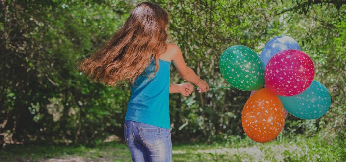 girl holding colorful balloons