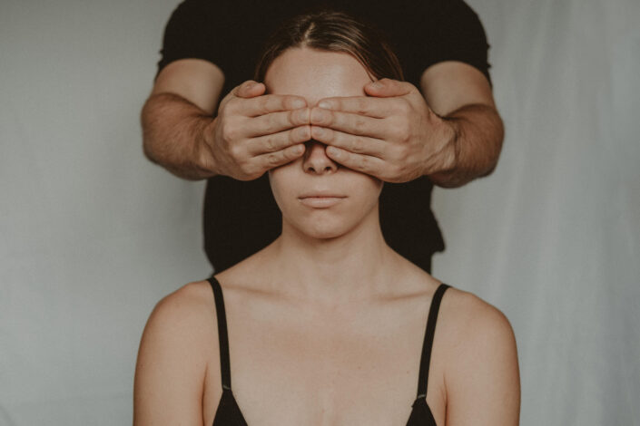 man covering woman's eyes with his hands