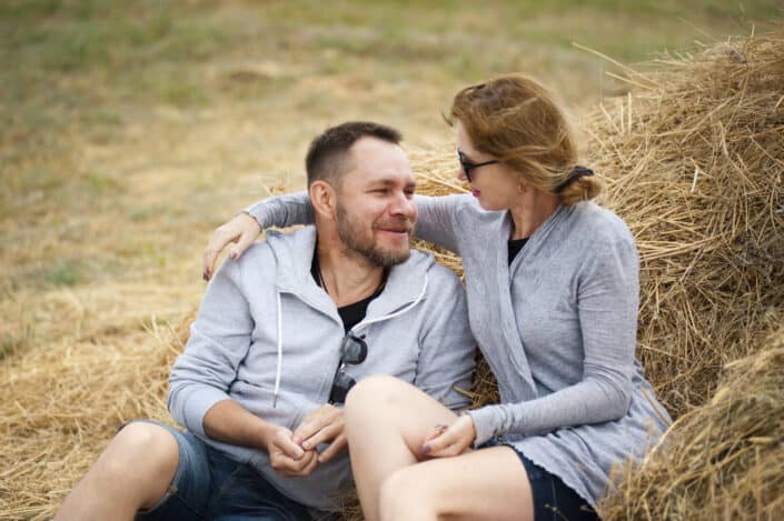 Couple enjoying moments together while sitting on a pile of dried hay