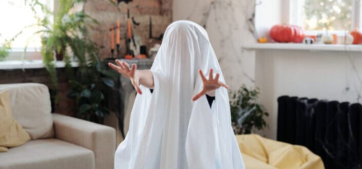 Kid covered in white blanket acting like a ghost