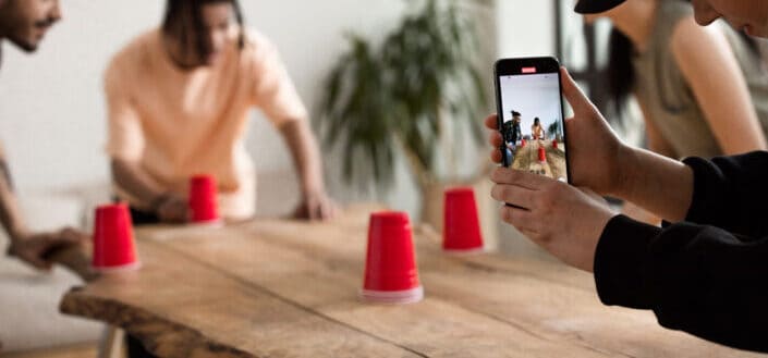 A guy recording while his friends are playing with red cups