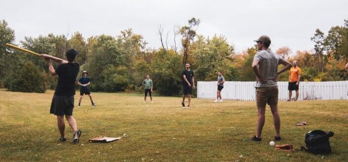 Men playing baseball outside the yard