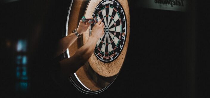 Person Picking Darts Pins on Board