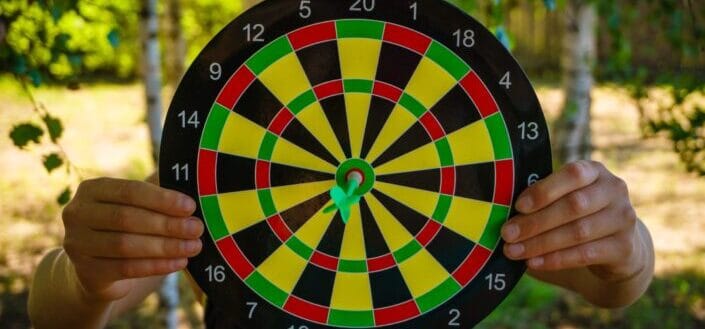 Person Holding Dartboard With Pin
